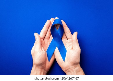 Blue ribbon cancer. Awareness prostate cancer of men health in November. Blue ribbon in hands isolated on deep blue background. Symbol of oncology affected man. Copy space - Powered by Shutterstock