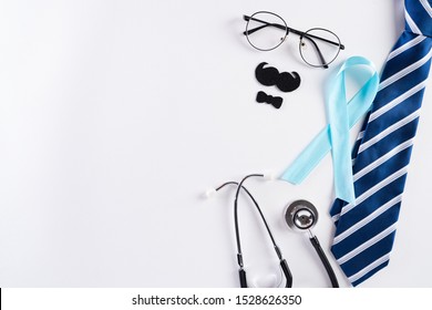 Blue ribbon with tie and stethoscope on white background representing an annual event during the month of November to raise awareness of men's health issues and prostate cancer with copy space.