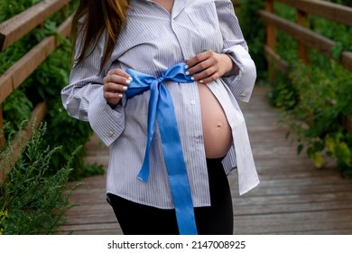 Blue Ribbon Tied In A Bow On The Belly Of A Pregnant Woman, Close-up Side View.