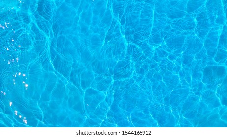 Blue Ripple And Wave Water In Swimming Pool. Water Surface  Blue Background. Top View And Copy Space For Summer Vacation .