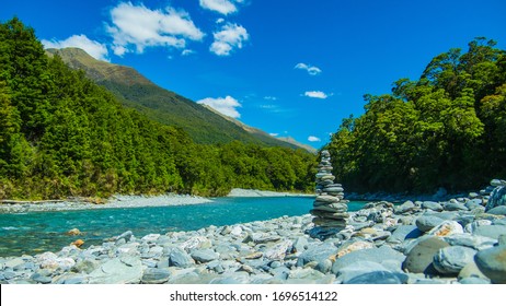 The Blue River With Stones, New Zealand. Green Trees And Blue Sky