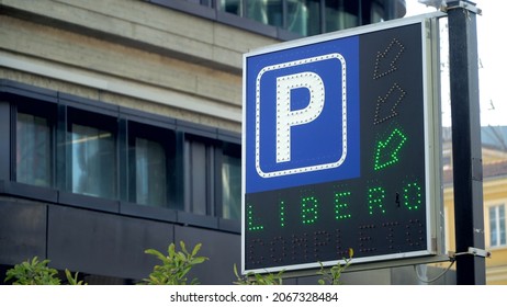 A Blue Road Sign Showing Motorists Where To Park In The City For Their Personal Travel Scenarios. Free Parking. Pointer. Cars And Traffic In The City. Paid Supermarket Parking 