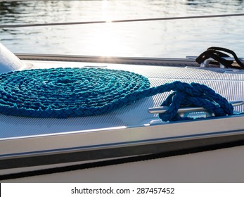 Blue rope coiled on dock and tied to metal cleat. sailboat yacht detailed part.