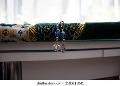 Blue Rosary Hanging From A Green Prayer Rug.