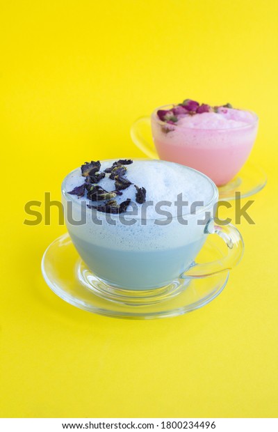 Blue and rose moon milk in glass\
cups on the yellow surface. Location vertical. Copy\
space.