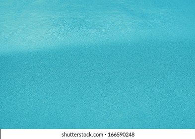 Blue Sandy Beach Background. Detailed Sand Texture And Water . Top View