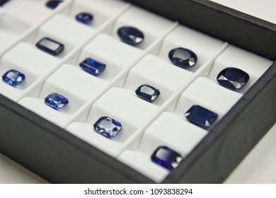A lot of Blue Sapphire Set of Blue Gems on white tray black edge many slot closeup to sockets 