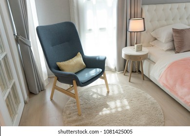 Blue Scandinavian Armchair Sitting In Bedroom With Side Table And Carpet