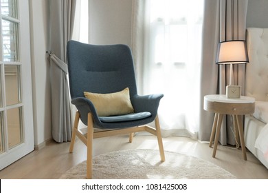 Blue Scandinavian Armchair Sitting In Bedroom With Side Table And Carpet