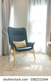 Blue Scandinavian Armchair Sitting In Bedroom With Side Table And Carpet