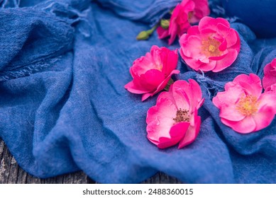 Blue scarf and pink roses on wooden floor. Empty space for blank text. Close up - Powered by Shutterstock