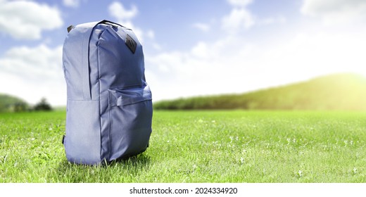 Blue school backpack on grass and landscape  - Shutterstock ID 2024334920