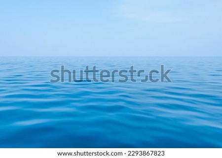 Blue sea with gentle waves and a sky of the same color as the sea, a peaceful ocean with small waves that are pleasing to the eye