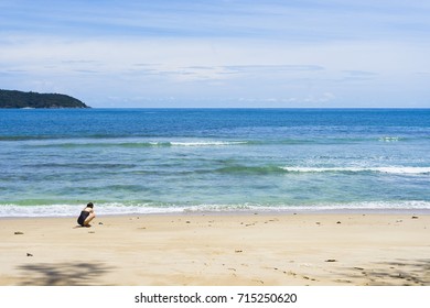 blue sea and sandy beach with woman walking