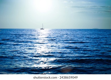 Blue sea surface background with sailboats sailing in the middle of the sea, atmosphere after sunset.