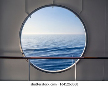 Blue Sea with view to horizon seen through porthole in white ship