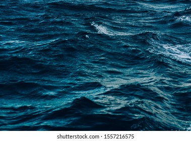 Blue Sea Wave Close Up, Low Angle View, Sunrise Shot. Background Image Of Aqua Sea Water Surface With Sunny Reflections Split By The Waterline, Aerial View. Ocean Wave Close Up. Strom Water Waves.