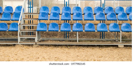 Blue seats on an empty grandstand in an outdoor beach volleyball stadium.