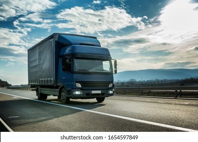 Blue Semi Trailer Truck On A Highway Driving At Bright Sunny Sunset. Transportation Vehicle