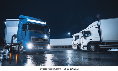 Blue Semi-Truck with Cargo Trailer Drives Off From Overnight Parking Space where Other Trucks are Standing. Long Haul Truck Leaves Parking Lot, Transporting Cargo / Goods Across Continent. Rainy Night - Shutterstock ID 1813109293