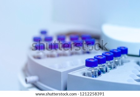 Blue shade picture of close up vials in autosampler of gas chromatography with spectrometer in chemical laboratory