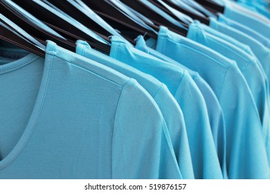 Blue shirts on black hangers in shop, fashion background