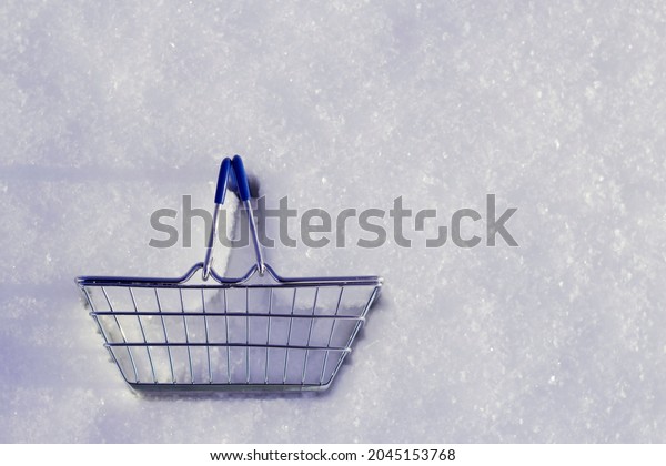Blue shopping\
cart in snow with top view. Shopping and buying gifts for winter\
holidays. Delivery in cold\
season.