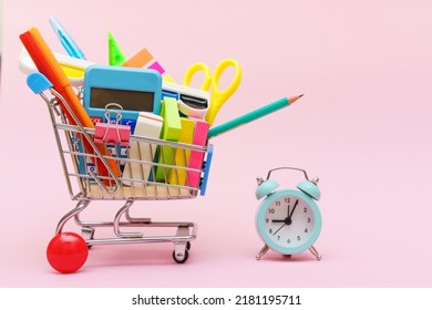 Blue Shopping Cart Or Trolley And Stationery Pen Pencil Clip Pin Rubber Isolated On Pink Background. Online Shopping Concept For School