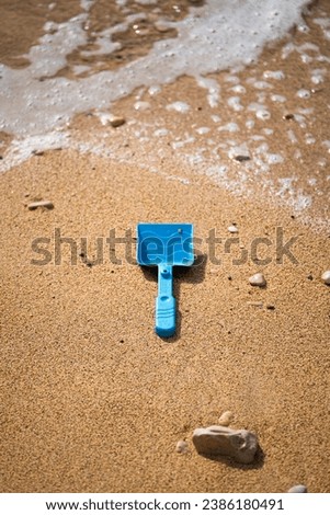 Blue shovel toy on wet sand at the beach