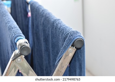 A Blue Shower Towel Dries On A Metal Clothes Dryer.