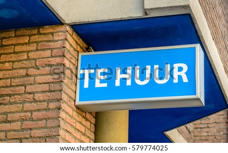 Blue sign at a brick wall with in the Dutch language and in white characters the text FOR RENT.