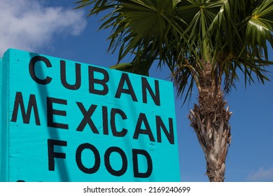 Blue Sign For Cuban Mexican Restaurant In Florida. Palm Trees And The Blue Sky In The Background
