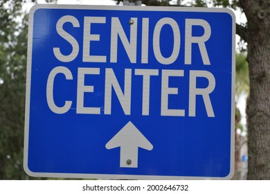 A Blue Sign Instructs Senior Center Ahead With An Arrow Pointing Up.