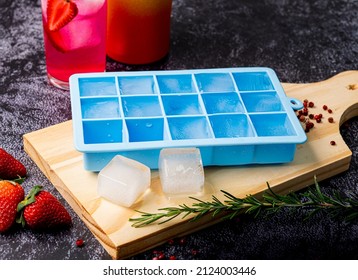 Blue silicone ice cube tray on table with fruit and strawberry drink