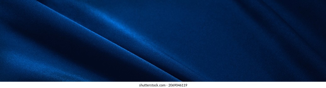    Blue silk satin. Folds in the fabric. Elegant background with copy space for design. Web banner. Website header.                            