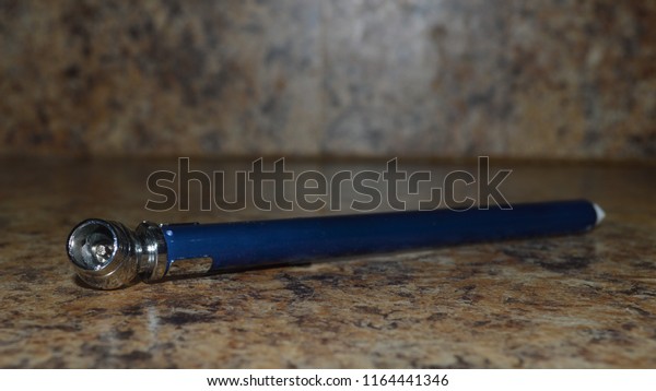 A blue and silver\
tire pressure gauge on a brown counter top. Selective focus on the\
silver part.