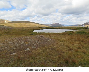 Blue skies with low cloud and a small lake on a mountain