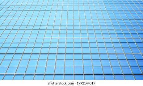 Blue sky and clouds reflected in windows of modern office building. Modern glass facade. 