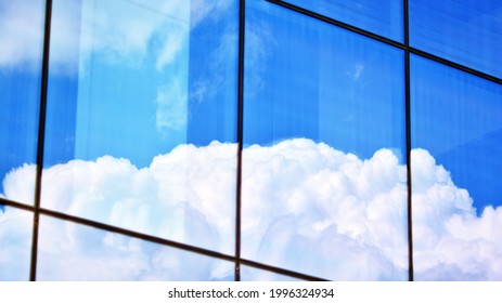 Blue sky and clouds reflected in windows of modern office building. Modern glass facade. 