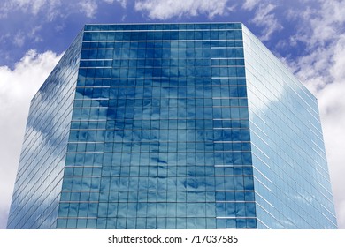 Blue sky and clouds reflecting in windows of modern office building