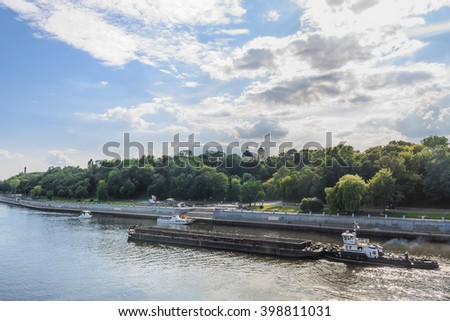 Blue sky, clouds, river water, green trees, beach, boats in spring or summer season landscape