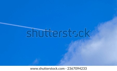 Blue sky with a contrail produced by an airplane.