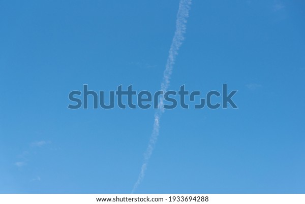 Blue sky cut by smoke from airplane\
fuel. Aviation kerosene waste. Aircraft fuel trail on the horizon.\
Environment pollution. Commercial\
aviation.