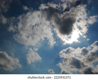 Blue Sky, Dark Clouds And Sun Shining Through