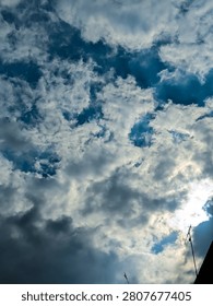 Blue sky with dramatic clouds and sunlight above a residential area, showing natural weather conditions, clean air, and a healthy outdoor environment suitable for climate and environmental concepts.