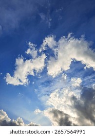 Blue sky with dramatic white clouds and sunlight, perfect for weather backgrounds, nature scenes, and atmospheric stock content.