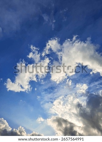 Blue sky with dramatic white clouds and sunlight, perfect for weather backgrounds, nature scenes, and atmospheric stock content.