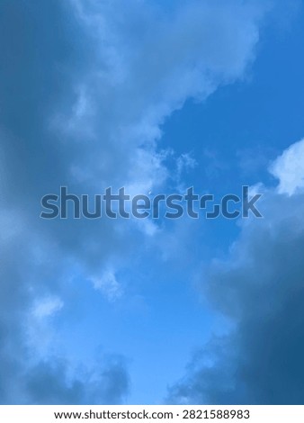 Blue sky with large clouds and a visible moon creating a peaceful atmospheric cloudscape.