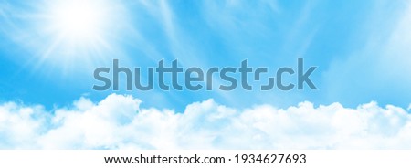 Blue sky with light clouds and bright sun. Wide summer sky backdrop