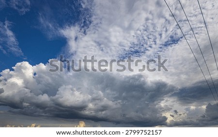 Blue sky meets fluffy, dramatic clouds. Darkening storm clouds loom overhead